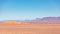 View of an arid landscape in the desert with a village and brown mountains in the background