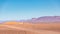 View of an arid landscape in the desert with a village and brown mountains in the background