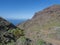 View of arid subtropical landscape of Barranco de Guigui Grande ravine with cacti and palm trees viewed from hiking