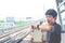 View of asian  man stand and looking at his watch while waiting for something or worrying about time. Motion train as background.