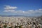 View of Athens cityscape showing lowrise white buildings architecture, mountain, trees, white cloud and blue sky background