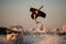 view of athletic man making extreme jump showing trick in the air on wakeboard against the sky