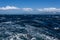 View of Atlantic Ocean and distant mountains, choppy water, calm blue sky with white clouds