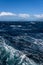 View of Atlantic Ocean and distant mountains, choppy water, calm blue sky with white clouds