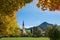 View through autumnal colored maple branches to saint leonhard church schliersee