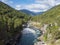 View on azure Rauma river canyon at Romsdalen valley with snow capped peaks of mountains, rocks and green forest. Blue sky white