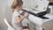 The view from the back, a bright little girl looks at the children's notes and plays the electronic piano