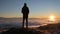 View From the back. A lonely standing man high in the mountains looks at the setting sun and the sunset horizon with a