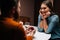 View from back loving young man making proposal for marriage to amazed pretty woman sitting at table with candles, marry