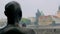 View from back of metal statue of human, looking on old traditional buildings in Prague