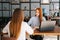 View from back to female applicant during job interview talking with young woman employers sitting at desk opposite each