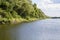 A view of the bank of the river along which stretches dense thickets of trees and shrubs