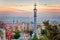 View of Barcelona from Park Guell at the sunset. In the foreground, detail of the colourful roof of the main entrance building.