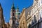 View of Baroque Church of Saint Nicholas, green dome and bell tower with clock, sunny winter day, snow on red roofs, Mala Strana