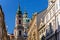 View of Baroque Church of Saint Nicholas, green dome and bell tower with clock, sunny winter day, snow on red roofs, Mala Strana