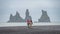 View of basalt stacks Reynisdrangar, black sand beach near Vik and two people in horseback riding, South Iceland, summer