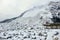 The view from a base of a mountain where a huge rock slide took place. Huge boulders line the mountain covered in snow.