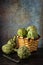 View of basket with artichokes on wooden table with knife, dark background