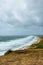 A view of a bay from a hill during a major storm with huge wave, choppy sea and foam with green vegetation on the foreground under