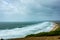 A view of a bay from a hill during a major storm with huge wave, choppy sea and foam with green vegetation on the foreground under