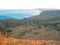 A view of the bay and huge hills by the sea after sunset, with a bright strip of sunbeam on the steppe grass.