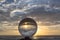 .view on the beach in beautiful sunset inside crystal ball placed on a timber by the sea.
