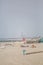 View at the beach with people taking sunbath on beach, lifeguard lifebuoys and a beach bar, lighthouse as background