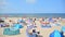 View of the beach. Tourists, sunbeds and windbreaks on summer hot day. Tourists on the beach on summer they sunbathe, rest and swi