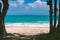 View of beatiful beach with turquoise water between two trees