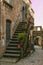 View of beautiful alley with flowers in the historic center of Civita di Bagnoregio village at sunset, Lazio