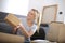 View of a beautiful caucasian female receiving a cardboard box, surrounded with boxes