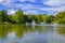 View of beautiful city park with pond, fountains, swimming ducks