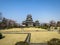 View of beautiful Matsumoto crow castle through landscape lawn with snow mountain and blue sky background during springtime