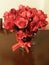 View of a beautiful red rose bouquet in a glass vase with a red bow on a wooden table