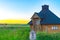 View of beautiful wooden hut on a plain wild grass field with sunset lights on background.