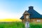 View of beautiful wooden hut on a plain wild grass field with sunset lights on background.