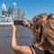 View from behind of a blonde woman taking a picture of buildings in Puerto Madero, Buenos Aires. Selective focus