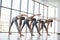 View from behind. Group of sportive girls in a spacious gym with big windows have training