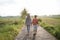 View from behind veiled mother and her son walk away from the road in the middle of rice field