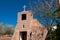 View of the bell tower, main entrance, and white cross of San Miguel Church in Santa Fe, New Mexico, USA