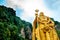 View from below of golden statue of hindu god murugan outside batu caves during cloudy day in kuala lumpur, malaysia