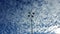 View from below on a lamp post with four lamps, against a blue sky with white cirrus clouds