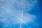 View from below of two high-flying airplanes whose routes cross on cloudy blue sky