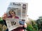 View from below of woman reading latest newspaper Le Monde with portrait of Hillary Clinton