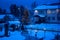 View of bench against christmas tree and shining lantern through snowing. Blue tone. Night shot.