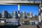 View beyond concrete construstion frame on marina with modern silver office buildings five boats against blue sky