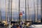 View beyond sail masts on lighthouse with red roof of mediterranean Harbour on cloudy day