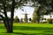 View beyond trees over green meadow with sheep herd on ancient windmill in autumn - Xanten, Germany