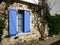 View of blue lattice window with a blue wooden shutter in a stone facade in Alacati, Turkey