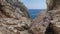 A view of the blue sea with a single yacht in the distance from the rocks on the seashore. Lloret de Mar, Catalonia, Spain.